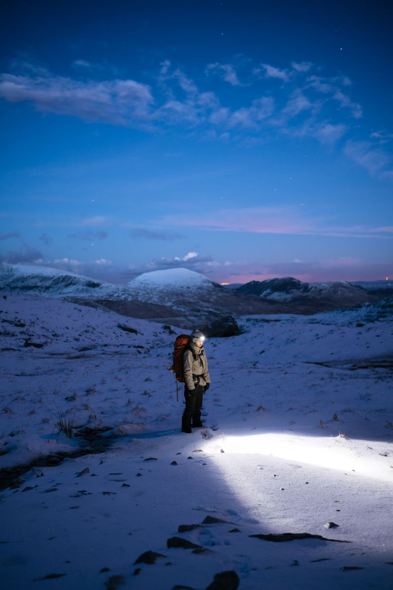 Hiker wearing a headlamp in snowy terrain
