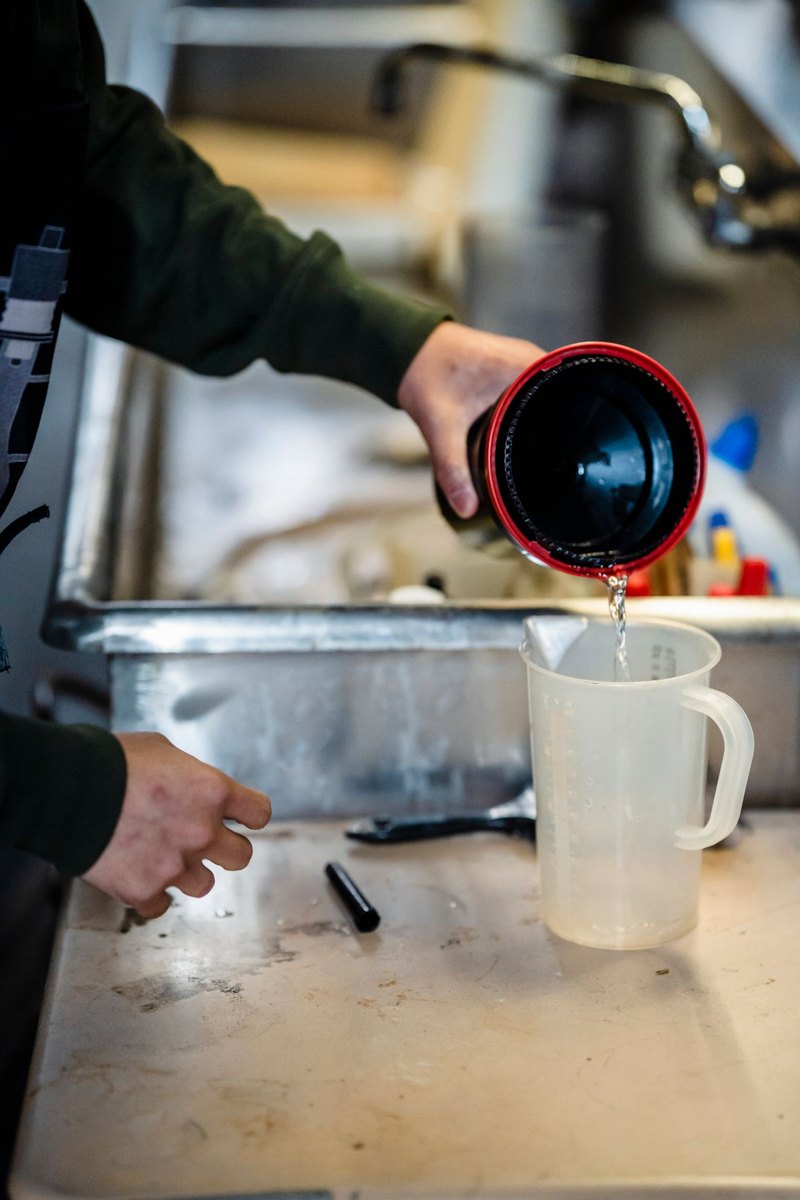 Liquid being poured into a measuring jug at a sink