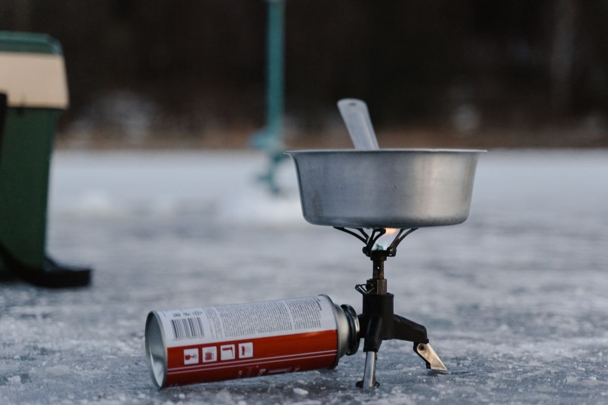 Camping stove and fuel canister set outdoors on snow