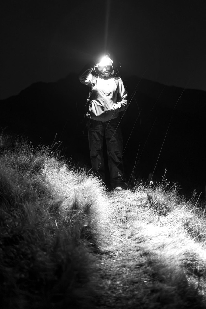 Hiker using a headlamp on a dark trail