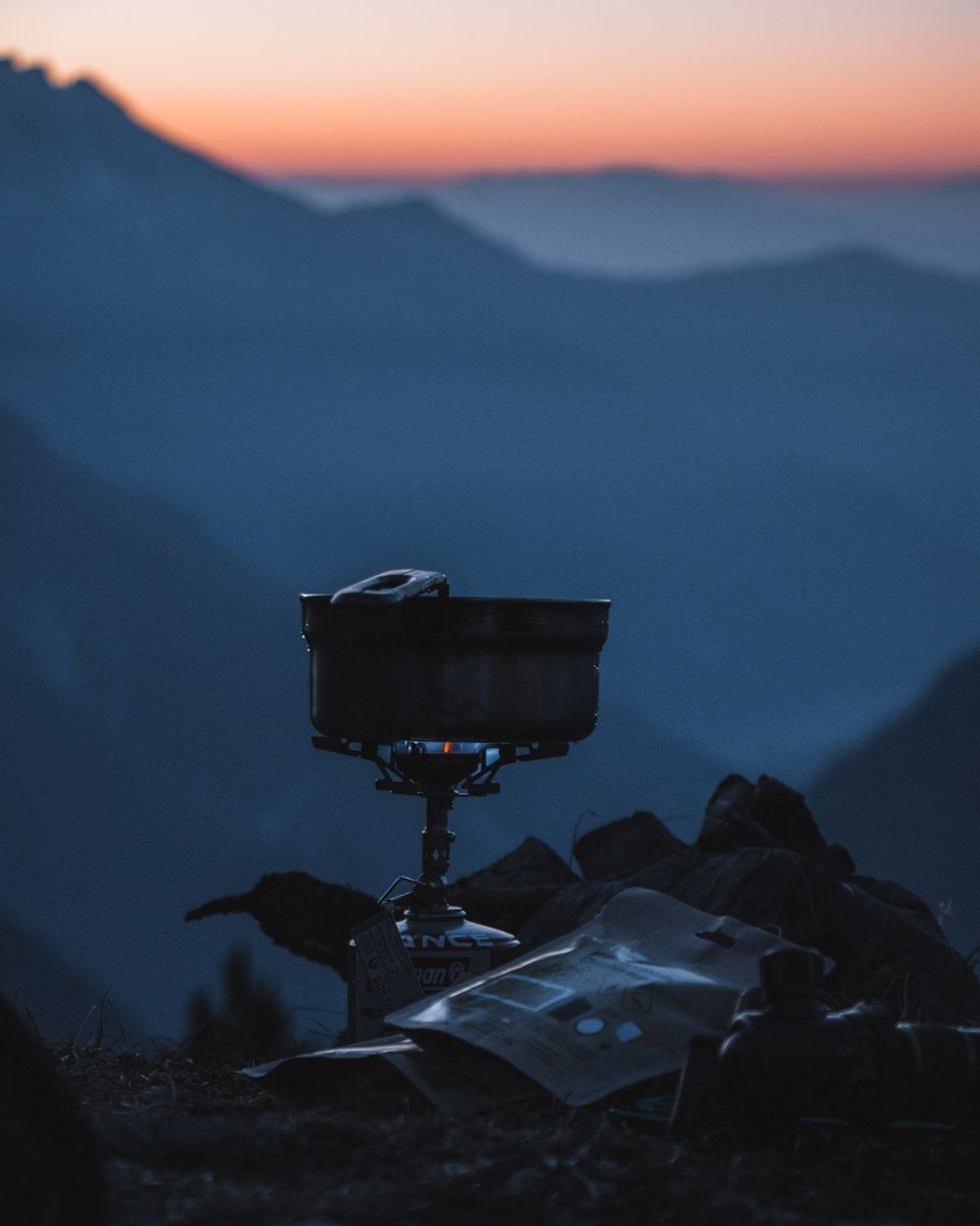 Cooking pot on a camping stove outdoors with mountains beyond