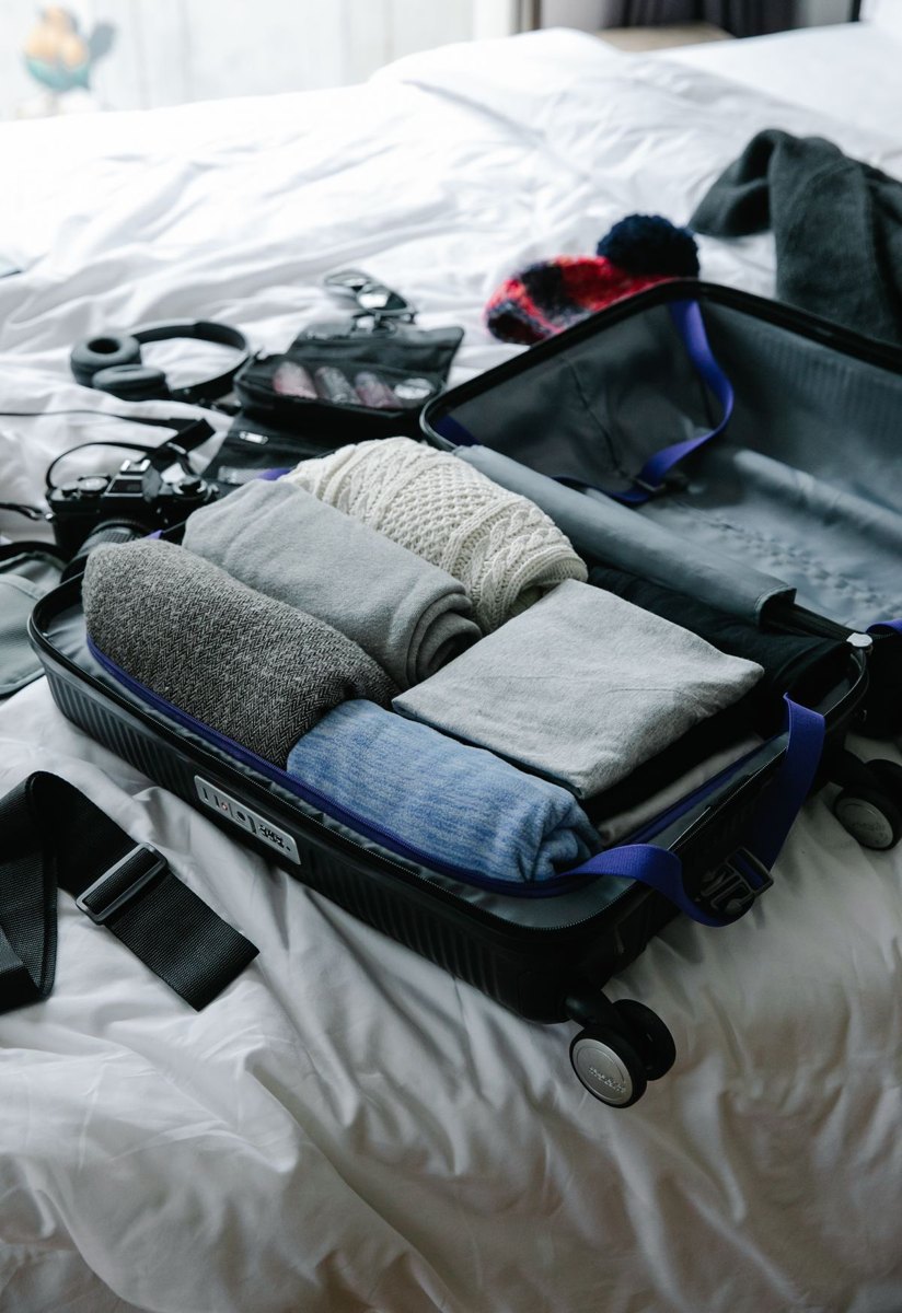 Open suitcase with neatly packed clothes on a bed
